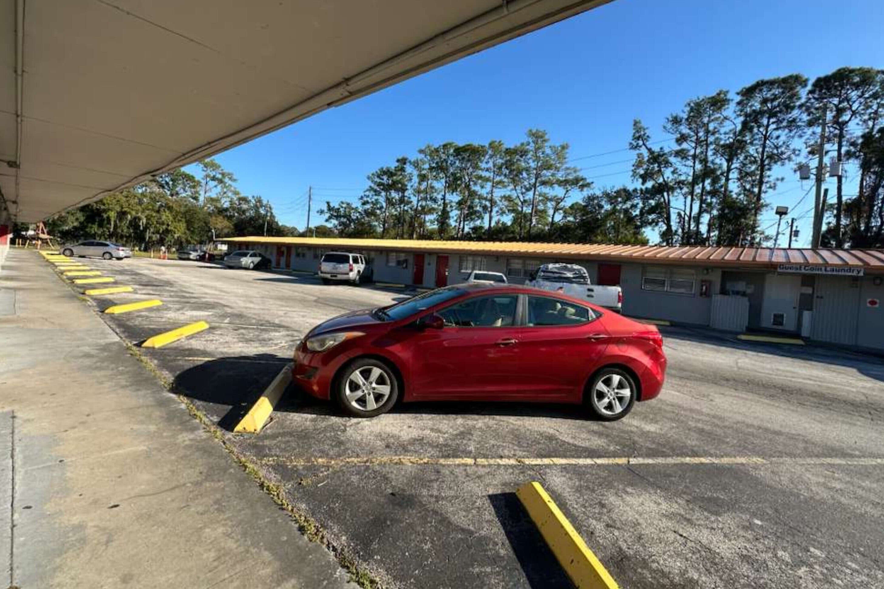 A parking lot with a red car parked in a marked space.