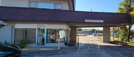 A hotel entrance with a covered walkway, a sign indicating a clearance of 8 feet, and a parking lot with cars.