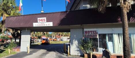 A motel with a clearance sign of 8 feet, an American flag, and a sign for the motel.