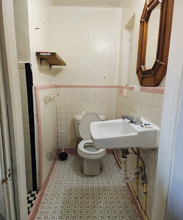 Ein kleines Badezimmer mit Fliesen, einer Toilette, einem Waschbecken und einem Spiegel.