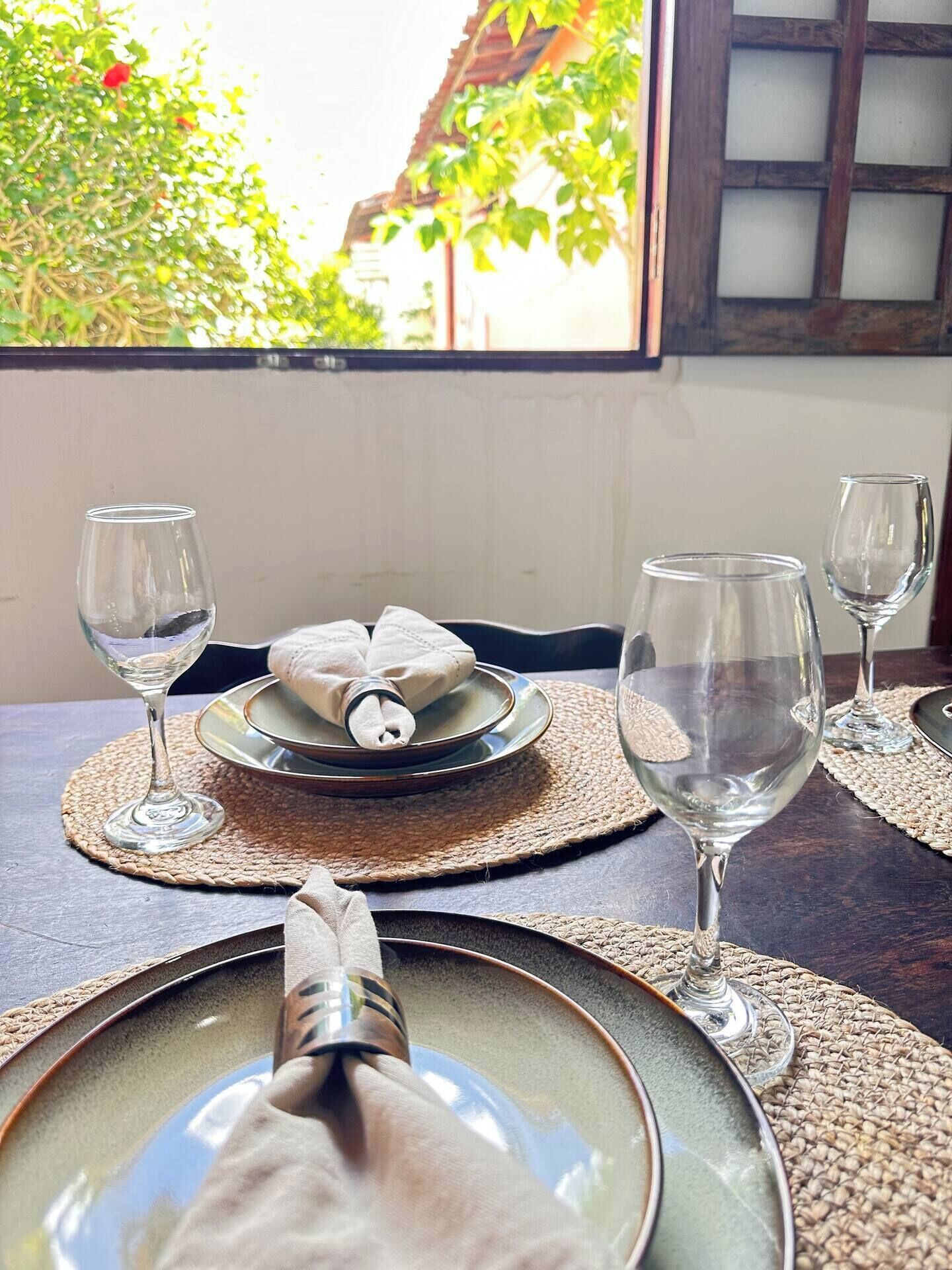 A dining table with plates, glasses, and a napkin holder.