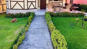 A traditional house with a tiled roof, a front porch with wicker furniture, and a well-maintained garden with a paved walkway. - Beautiful and cozy house! (Novo Gravatá Gravatá)