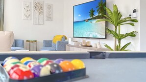 Un salon moderne avec un téléviseur à écran plat, un canapé, une table basse et une plante en pot.