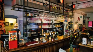 Eine Bar mit Regalen voller Flaschen und Gläsern, einer Registrierkasse und einem Gumball-Automaten.