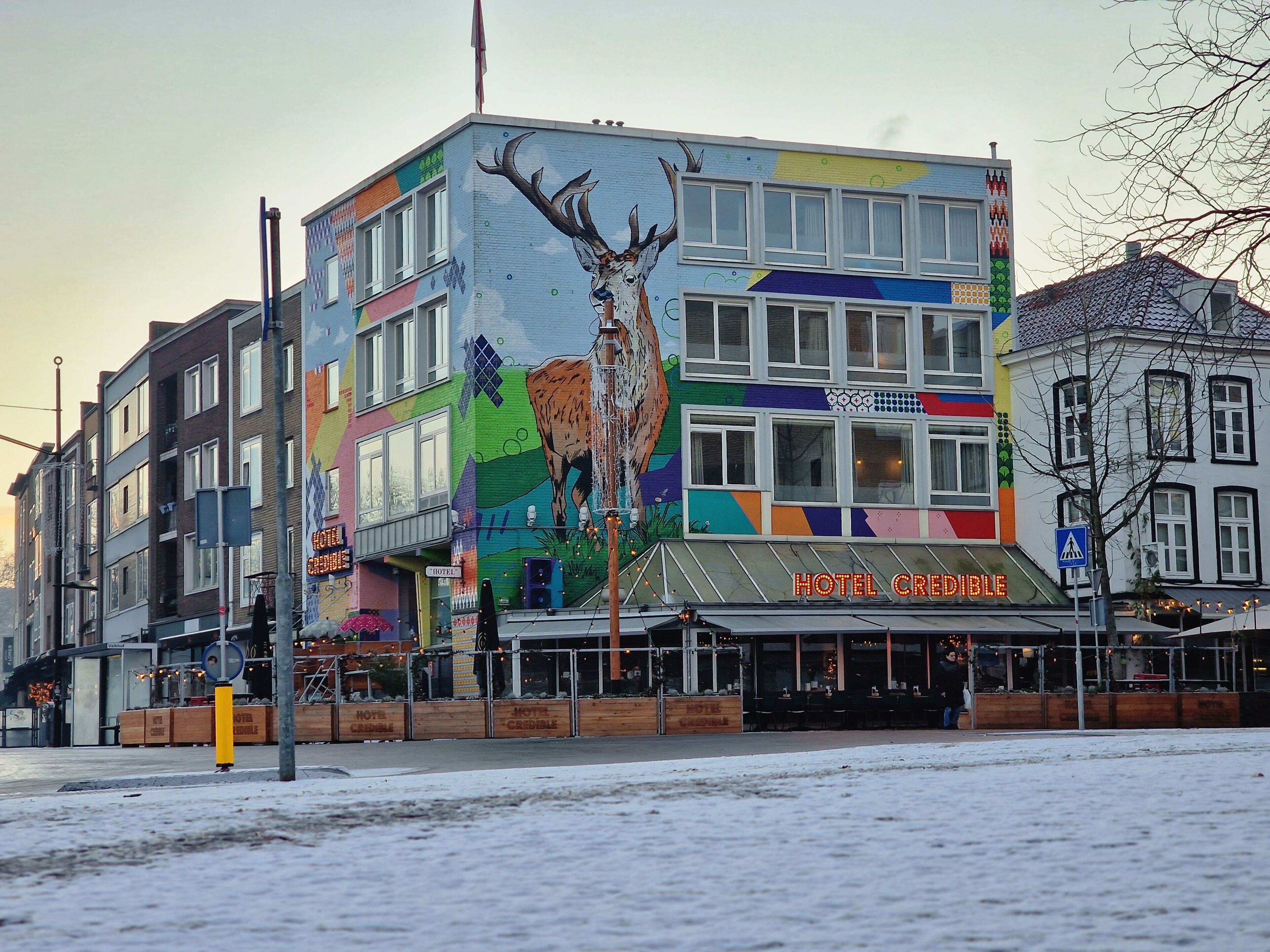 Un bâtiment aux couleurs vives, orné d’une grande fresque représentant un cerf et d’une enseigne indiquant « HÔTEL CREDIBLE ».
