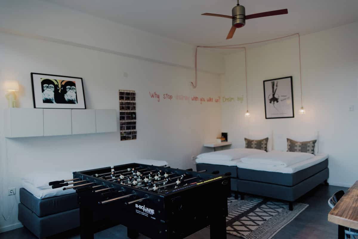 A modern bedroom with a bed, a sofa, and a foosball table.