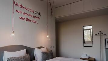 Una habitación de hotel moderna con una cama grande, una mesita de noche, un espejo en la pared y una cita motivacional.