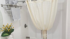 Une salle de bain avec une baignoire, un lavabo, un porte-serviettes et un vase de fleurs.