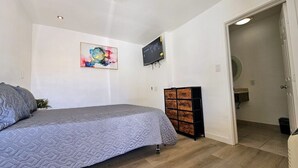 Une chambre à coucher avec un lit, une télévision et une armoire en bois.