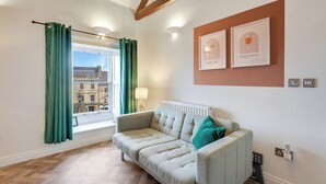 Una sala de estar moderna con un sofá, una ventana con cortinas y dos cuadros en la pared.
