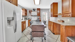 Una cocina moderna con armarios de madera, un refrigerador de acero inoxidable, un microondas y una mesa de comedor con sillas.