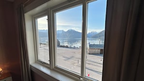 A room with a large window overlooking a parking area and mountains. - Sognefjord Gjesteheim (Vik)