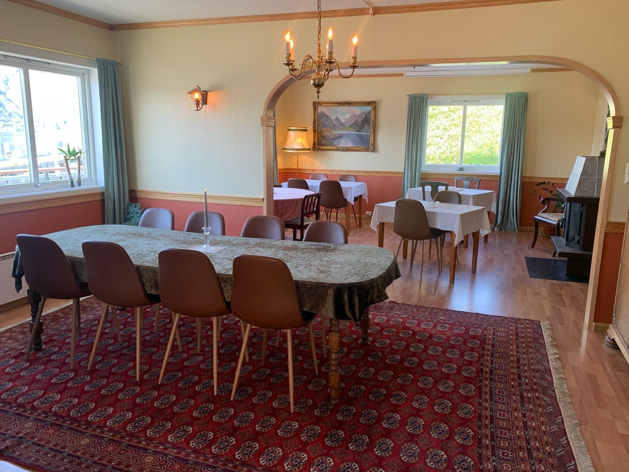 Un espace repas comprenant une grande table, des chaises, un lustre et une cheminée.