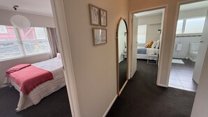 A bedroom with a bed, a large mirror, and a view into another room. - Retro Russell Retreat - Mins to Ferry, Beach, Eats (Russell)
