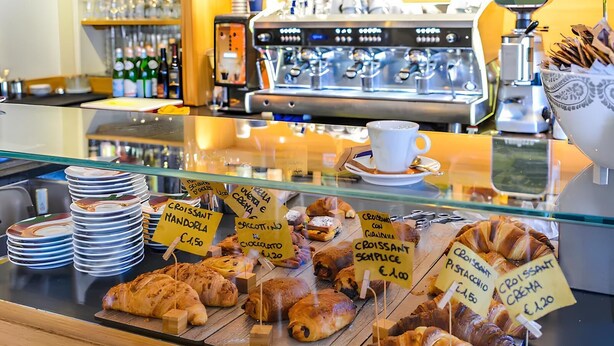 A bakery display with various pastries and a coffee machine in the background. - TAWHID ACCOMODATION (Rome)