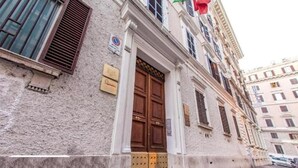 A building with a large wooden door, a signboard, and a window with shutters. - TAWHID ACCOMODATION (Rome)