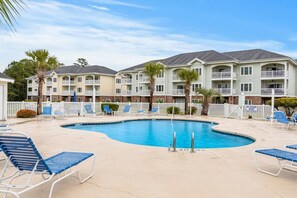 A pool area with lounge chairs and a no lifeguard sign.