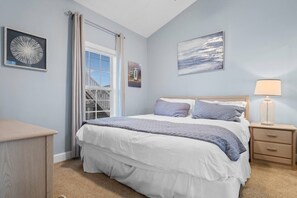 A bedroom with a bed, a nightstand, a lamp, and a window with curtains.