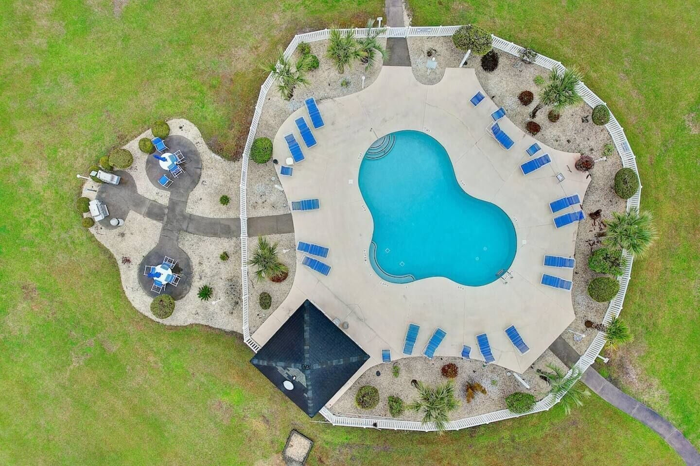 Vista aérea de una zona de piscina con múltiples tumbonas y un pequeño espacio de estar circular.