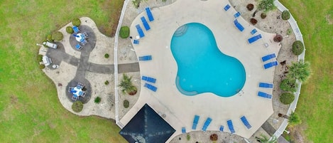 Vista aérea de una zona de piscina con múltiples tumbonas y un pequeño espacio de estar circular.
