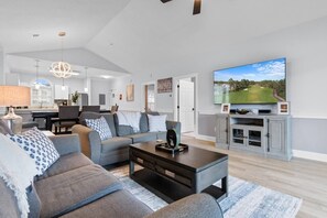 A modern living room with a flat-screen TV, a sofa, a coffee table, and a fireplace.