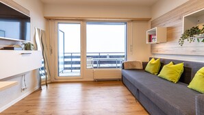 Un salon moderne avec un canapé gris, des coussins jaunes, un meuble blanc et un plancher en bois.