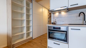 Une cuisine moderne avec des meubles blancs, un four encastré et un plancher en bois.