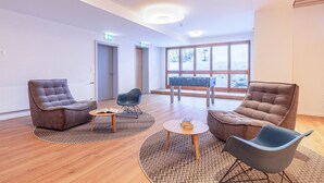 Een moderne lounge met drie banken, een salontafel en een tafelvoetbaltafel.