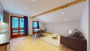 Ein modernes Wohnzimmer mit Holzboden, einem Essbereich mit Tisch und Stühlen sowie einem Sofa.
