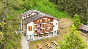 Un chalet à deux étages, avec des fondations en pierre, des balcons en bois et une piste de ski en arrière-plan.