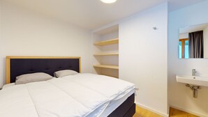 Une chambre à coucher comprenant un lit, une table de chevet, un miroir et des étagères intégrées.