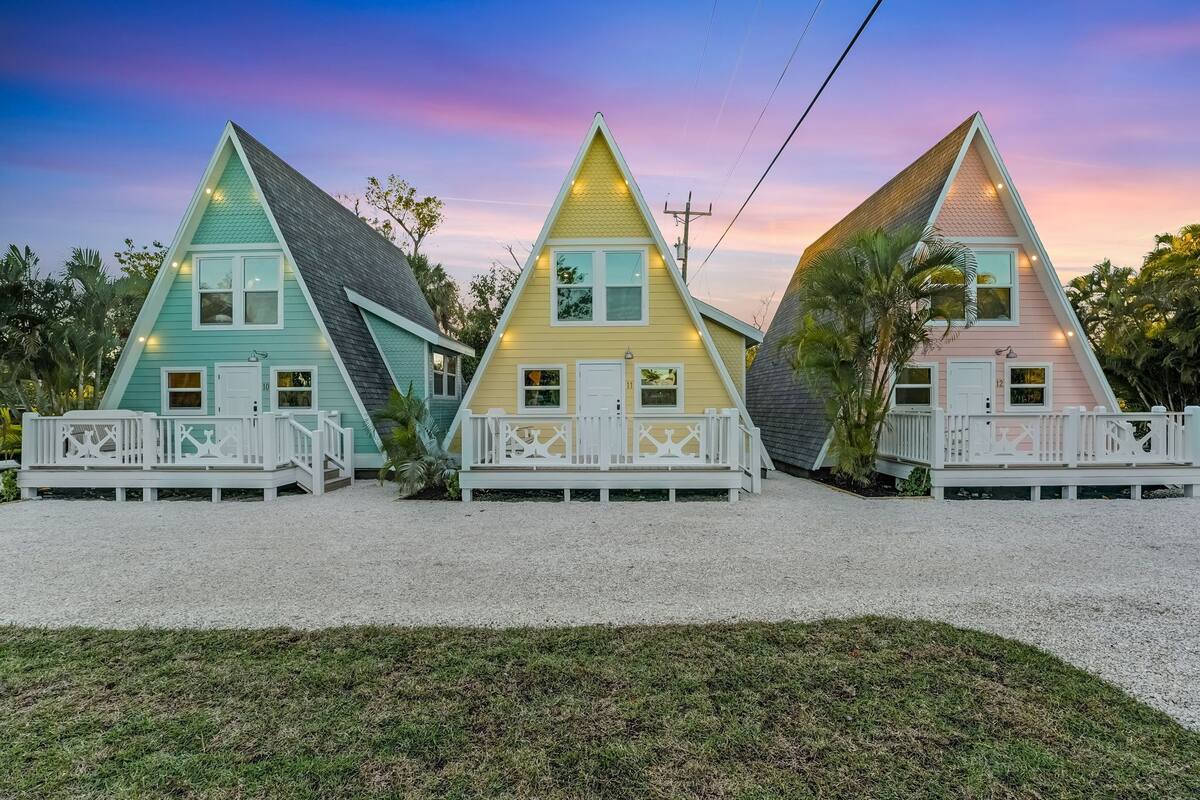 Three triangular houses with white railings and numbered doors.