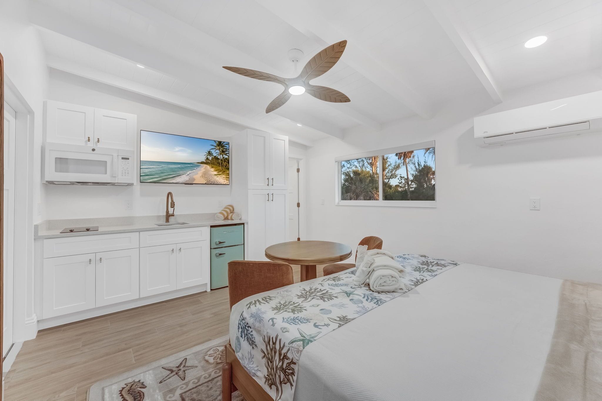Un dormitorio moderno con una cama, una mesita redonda y un televisor.