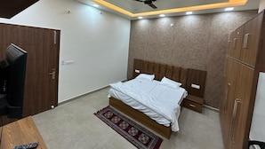 Une chambre moderne avec un lit, une armoire en bois, un ventilateur de plafond et un téléviseur.
