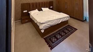 A bedroom with a bed, wooden wardrobe, ceiling fan, and recessed lighting.