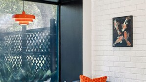 A modern living room with a grey armchair, a brown ottoman, and a red pendant light. - Perfect Pair: A Peaceful Cottage Vibe & Your Own Private Gameroom. (Covington)