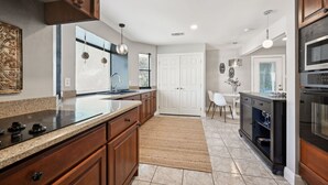 A modern kitchen with granite countertops, wooden cabinets, a built-in oven, and a dining area with a white table and chairs. - Perfect Pair: A Peaceful Cottage Vibe & Your Own Private Gameroom. (Covington)