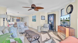 A spacious living room with a ceiling fan, a television, and a dining area in the background.