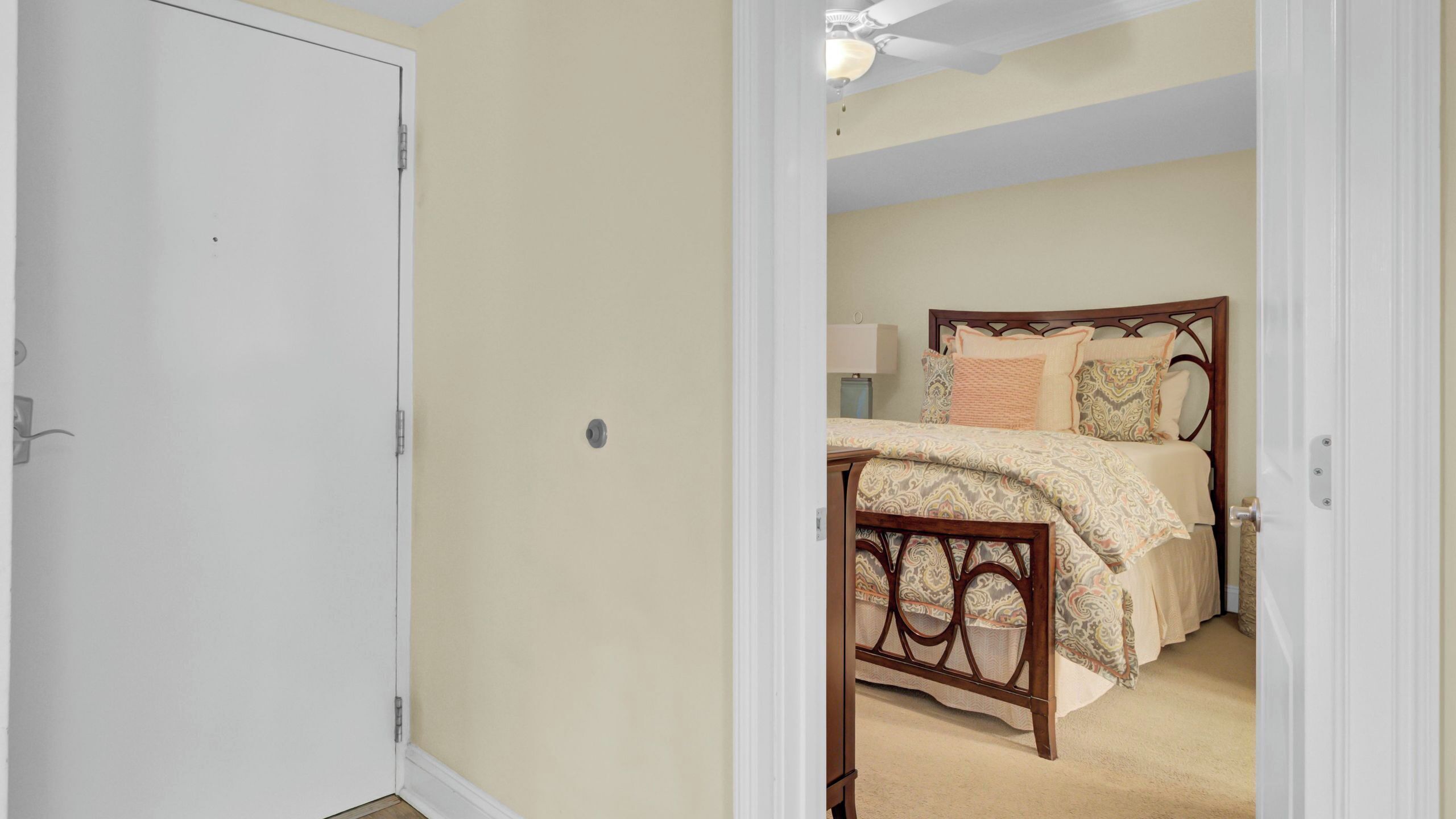 A bedroom with a bed, a nightstand, a lamp, and a door.