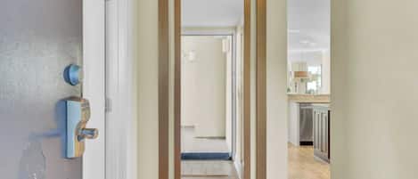 Un couloir avec un chambranle de porte miroitant qui mène à une cuisine.