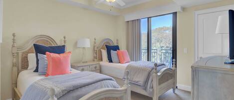 A hotel room with two beds, a ceiling fan, a large window with a view, and a dresser.