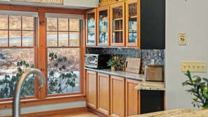 Eine Küche mit Holzausstattung, einem Toaster und Blick auf ein Bauernhof durch große Fenster.