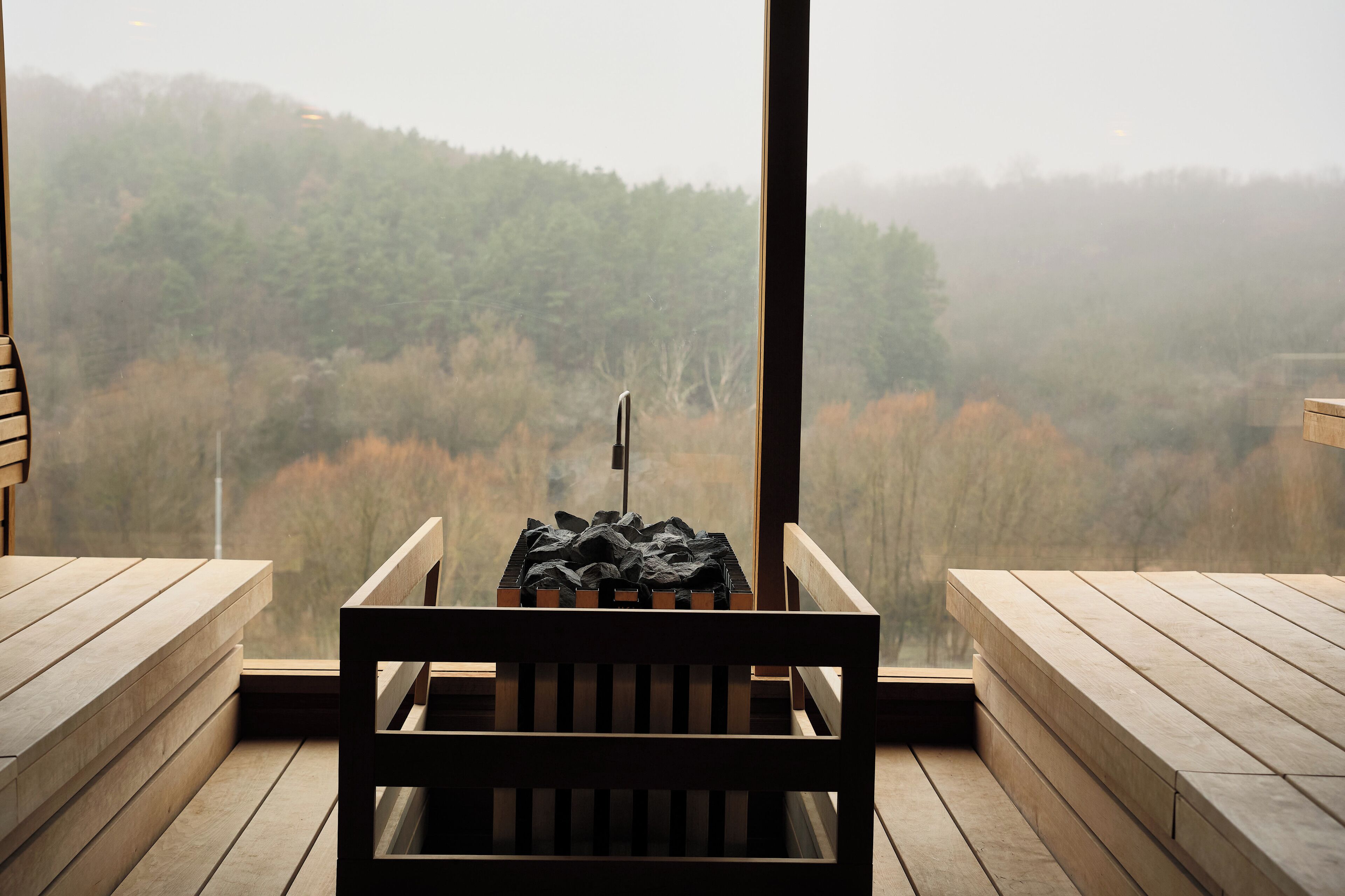 A wooden bench with a view of a forested landscape through a window.