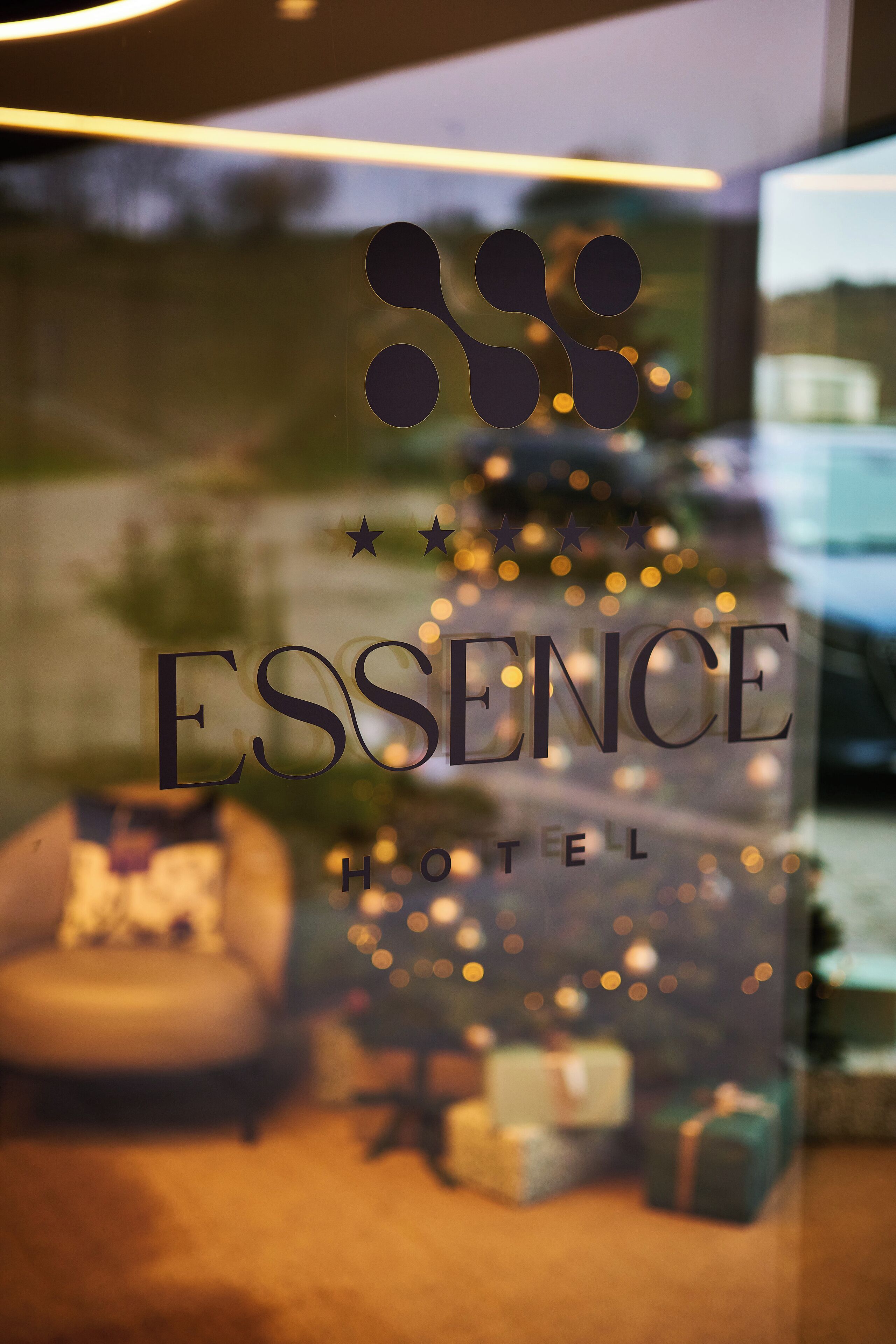 A hotel sign with the name "ESSENCE HOTEL" and a Christmas tree with presents.