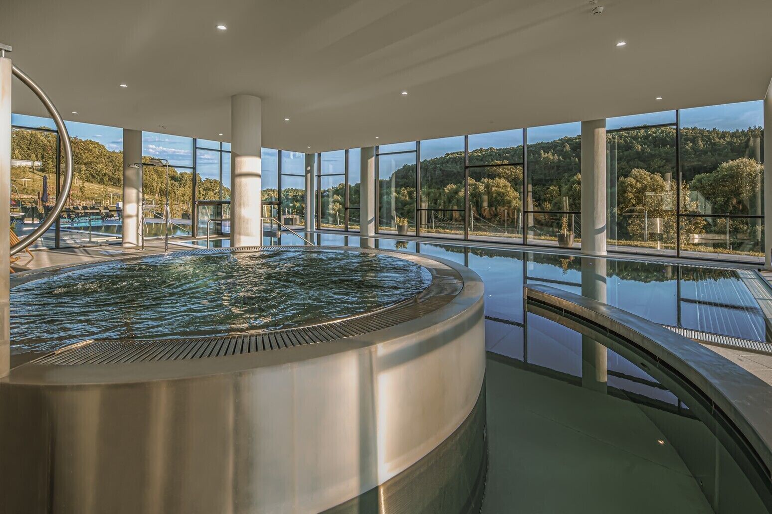 Ein moderner Innenpool mit Whirlpool, umgeben von großen Fenstern mit reizvoller Aussicht.