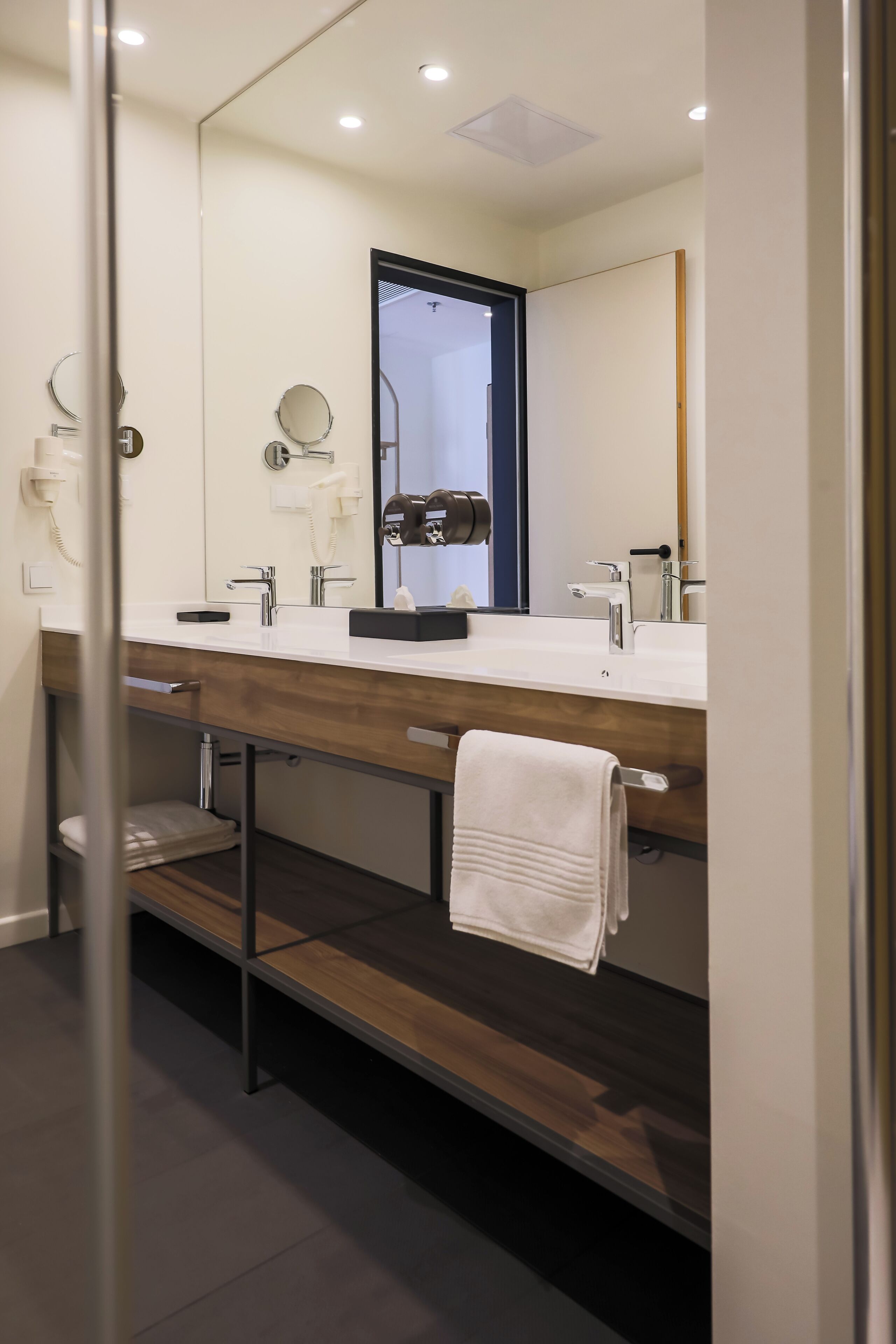 A modern bathroom with a double sink vanity, a towel rack, and a mirror.