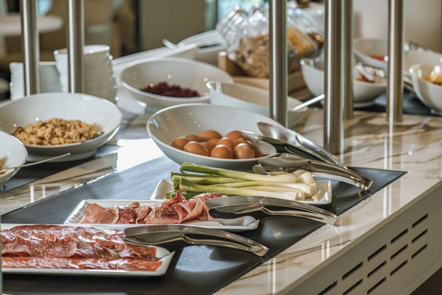 A buffet setup with various food items including meats, eggs, and vegetables.