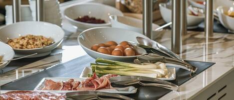 A buffet setup with various food items including meats, eggs, and vegetables.