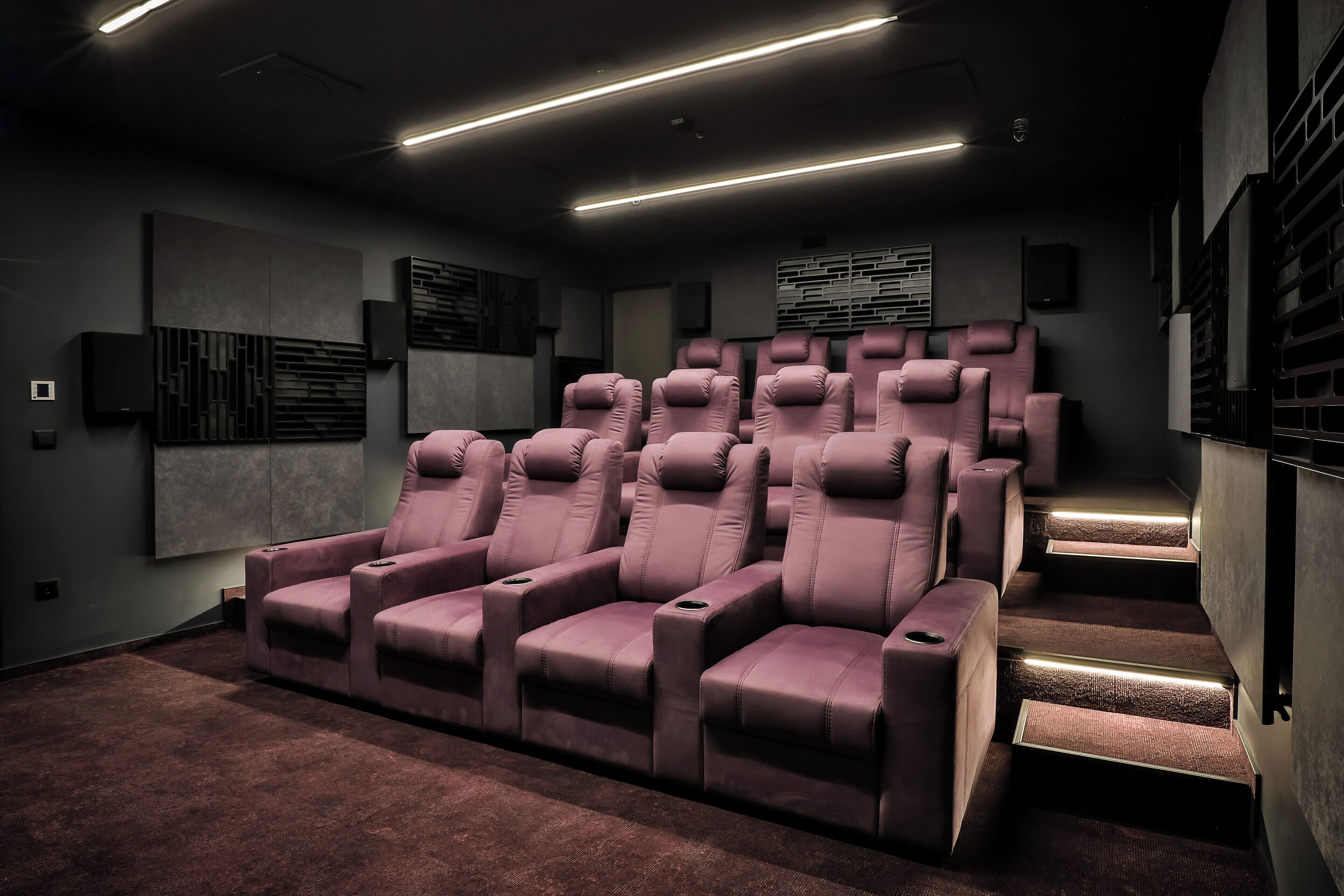 A home theater with plush seating, a carpeted floor, and a modern design.
