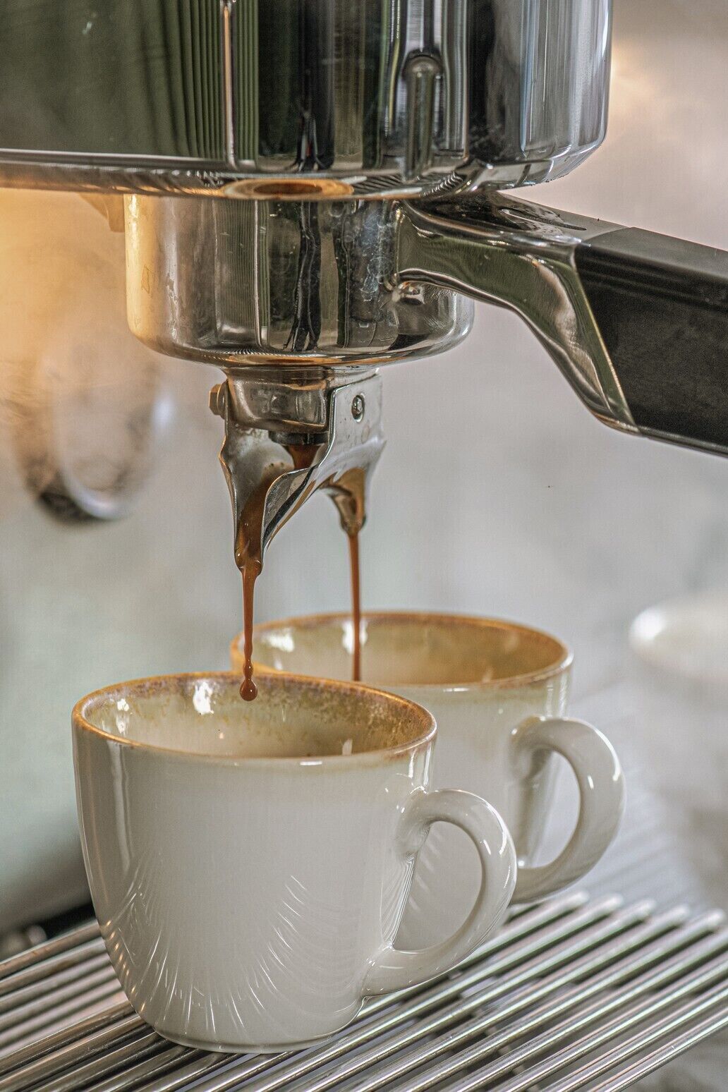A coffee machine dispensing espresso into two white ceramic cups.